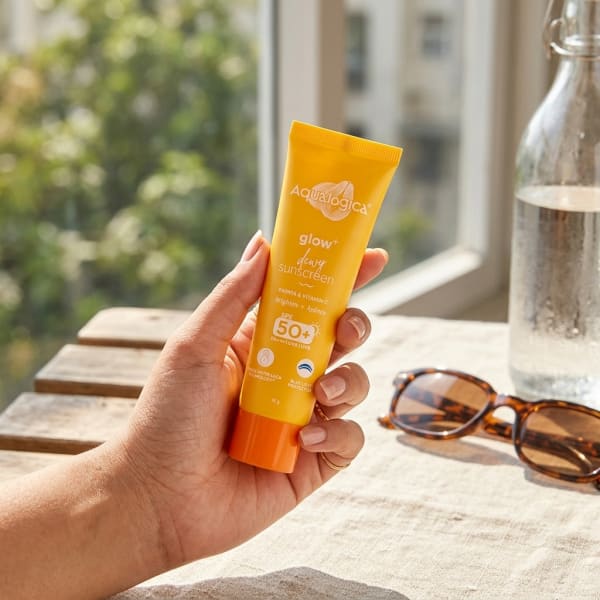 Aqualogica FREEBIE Glow+ Dewy Sunscreen 15g held in hand, candid photo
