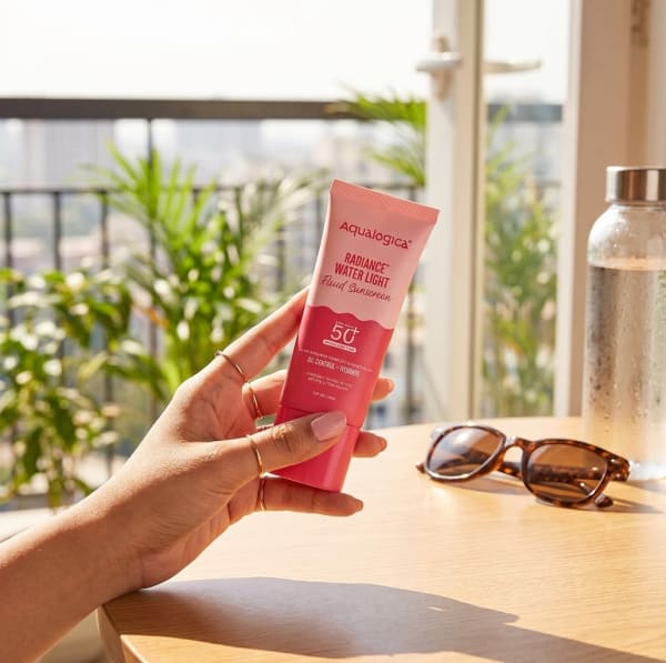 Aqualogica Radiance+ Water Light Fluid Sunscreen - 50g held in hand, candid photo