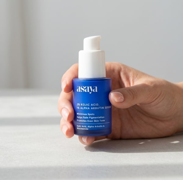 World of Asaya 2% Kojic Acid & 1% Alpha Arbutin Serum held in hand, candid photo