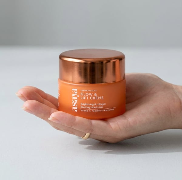World of Asaya Glow & Lift Crème - Peptide Moisturizer for Skin Brightening & Collagen Boosting held in hand, candid photo