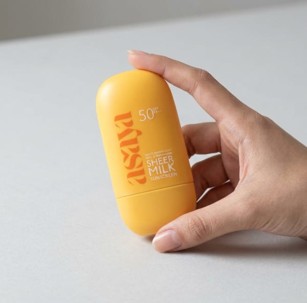 World of Asaya Sheer Milk Sunscreen - SPF 50 Matte Fluid Sunscreen held in hand, candid photo