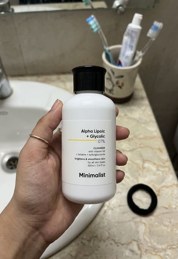 Minimalist Alpha Lipoic + Glycolic 7% Cleanser held in hand, candid photo