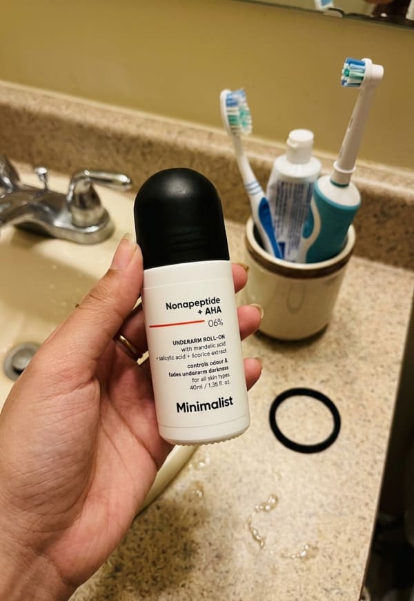 Minimalist Nonapeptide + AHA 6% Underarm Roll-On held in hand, candid photo