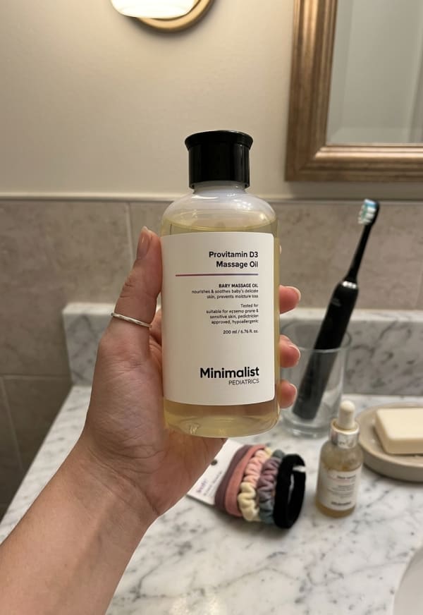 Minimalist Provitamin D3 Massage Oil held in hand, candid photo