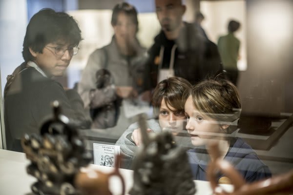 Kids peering through window at scupltures