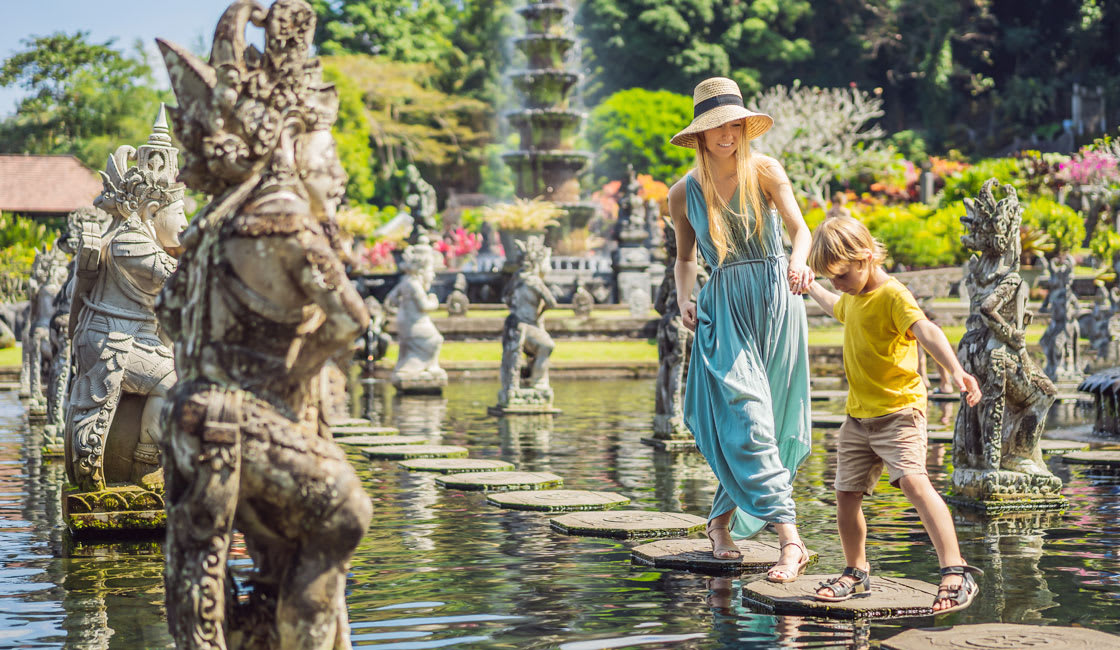 mommy and son walking throught a water garden full of stone statues