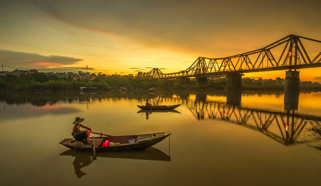 Small fishing boat at sunset near the bridge