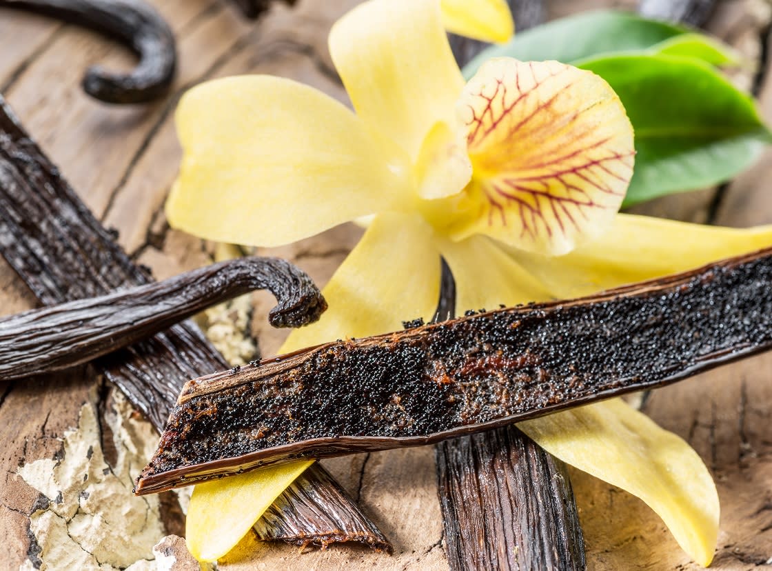 Palo de Vainilla Seco Y Orquídea Sobre Mesa De Madera