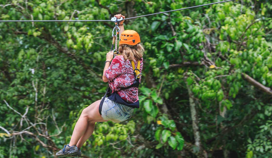 Young woman ziplning in the jungle