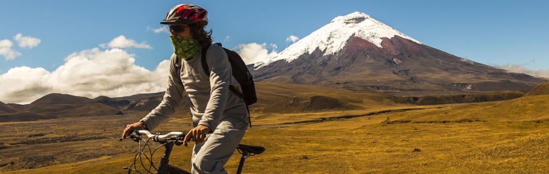 A person on a bicycle and mountain in the background