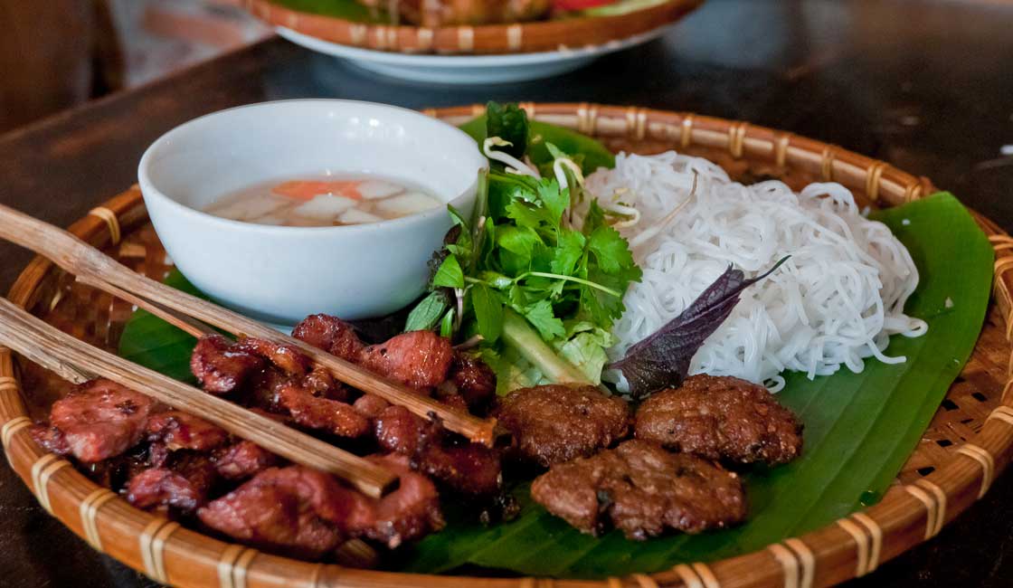 Grilled meat with rice noodles on a banana leaf