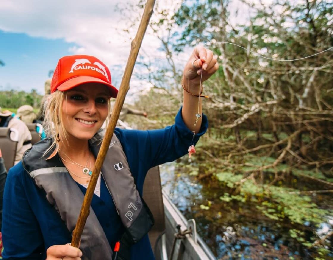 Happy Tourist holding a Cane, after fishing a Piranha