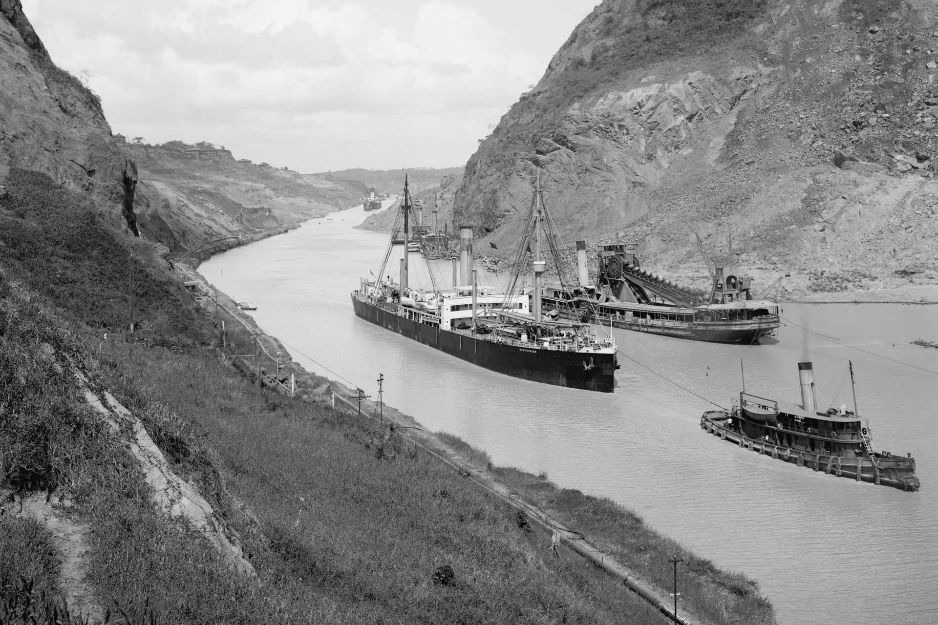 A black and white historical photo of ships navigating the Culebra Cut of the Panama Canal in 1915.
