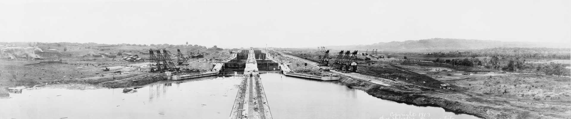 A black and white historical panoramic view of the massive Panama Canal locks under construction in 1913.