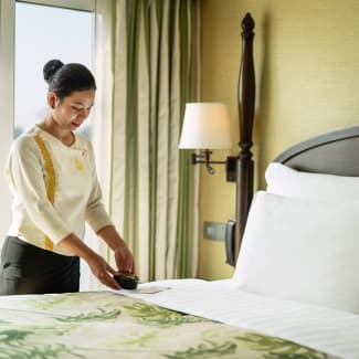 A housekeeping woman fixing a bed