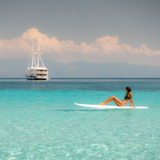 Woman on a paddle board looking at the Aliikai ship in the distance