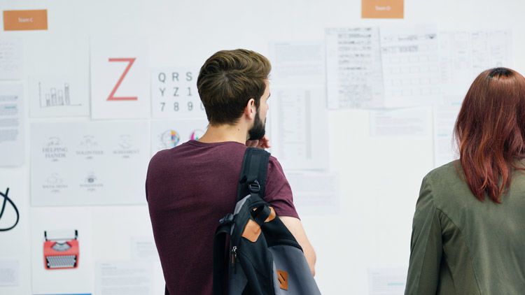 Students pondering ideas on a white board