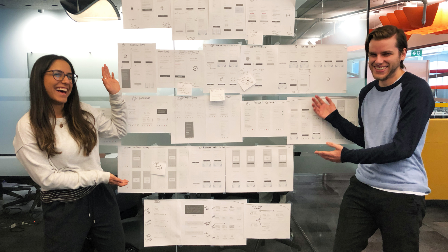 team members standing and smiling while pointing at a board