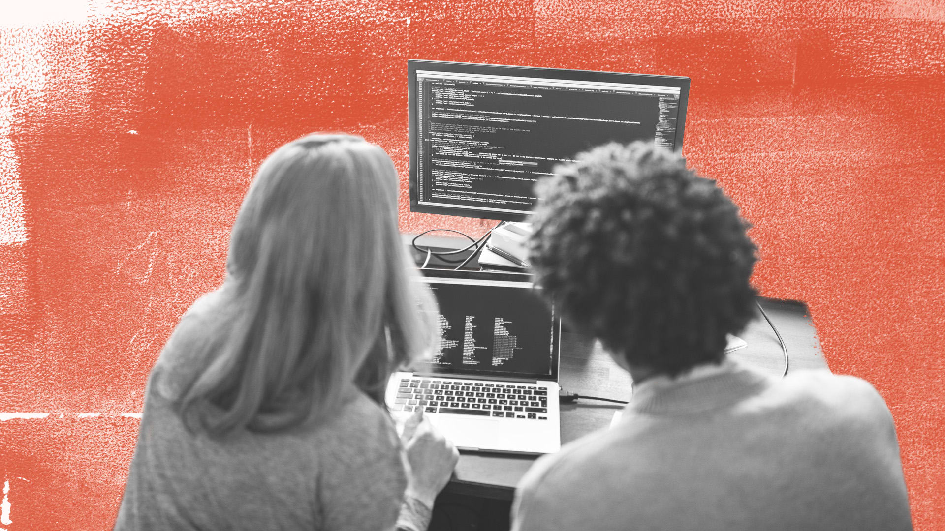 over shoulder view of two people looking at code