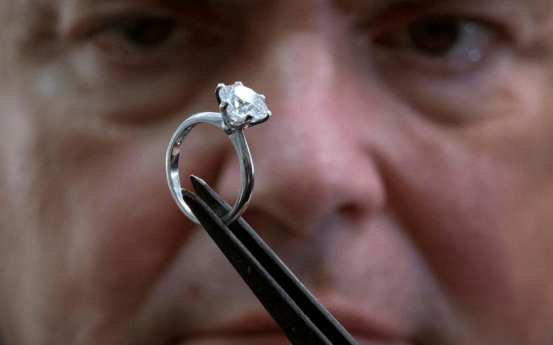 jeweler looking at diamond ring in tweezers