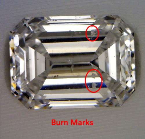 Rectangular step cut diamond with rough cloudy spots circled in red