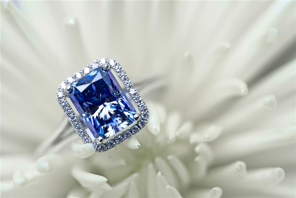 Radiant shape blue sapphire in a halo setting with treated blue diamonds