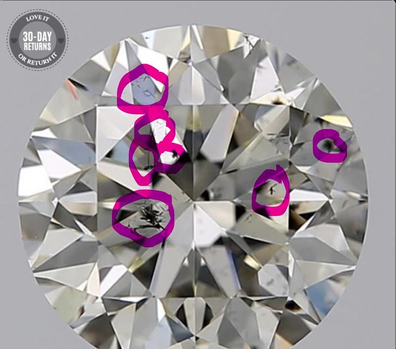 A close-up of a diamond with laser hole drilling inclusions circled in pink
