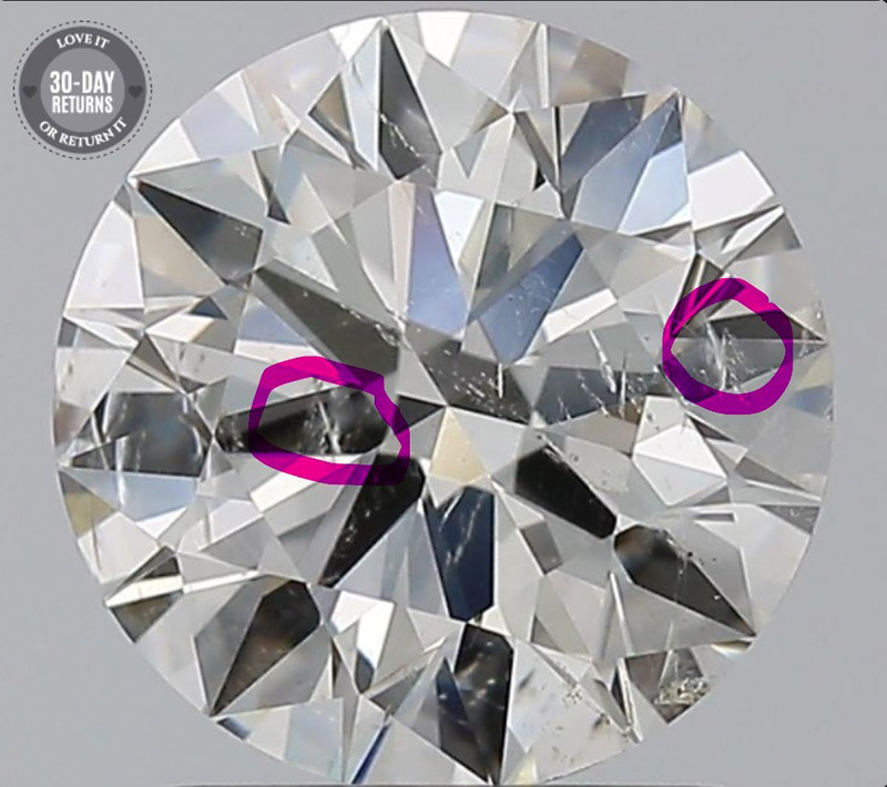 A close-up of a diamond with its feather inclusions circled in pink