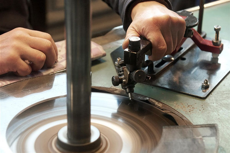 A person cutting a diamond manually on the polishing wheel