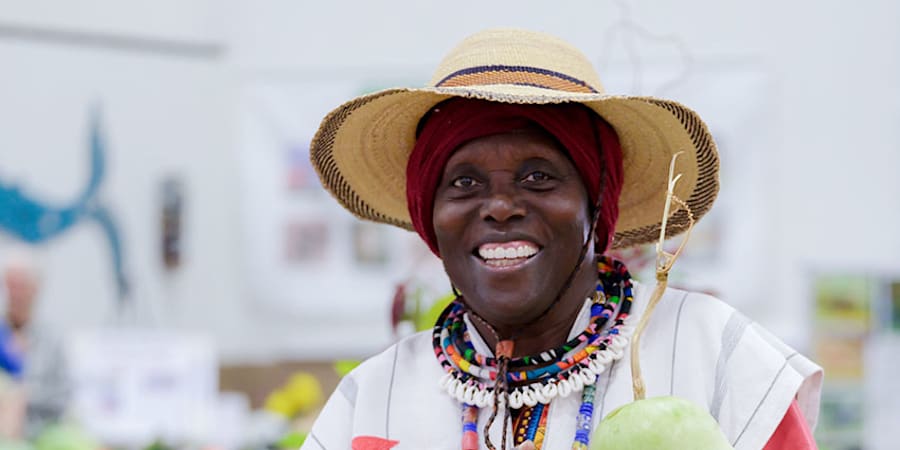 Makeda Cheatom in a straw hat holding a pale green gourd in the exhibit hall