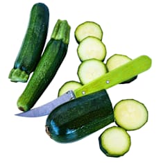 Sliced and whole Black Beauty zucchini with a green knife on a white background