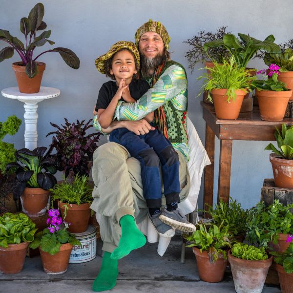 Ryan and his son sit in a chair surrounded by potted plants