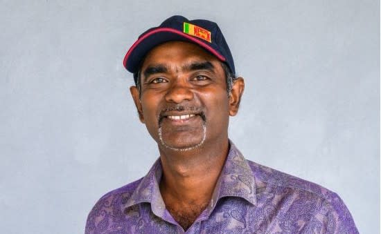 Don Weerakkody with purple shirt and dark hat with Sri Lanka patch on it