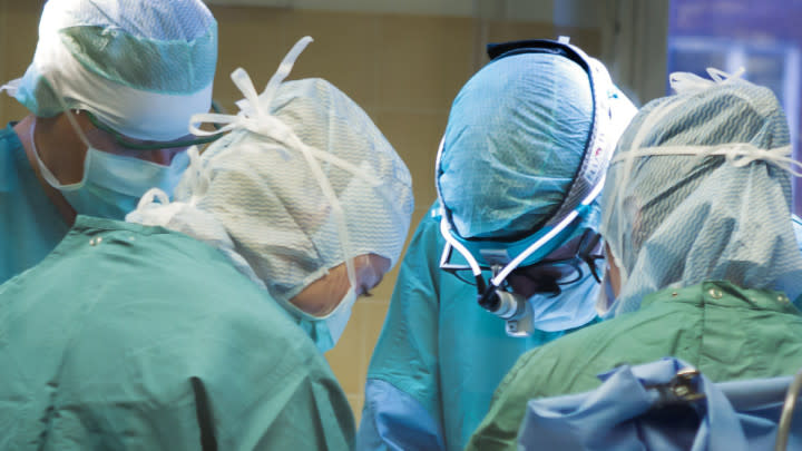 Vårdpersonal i gröna kläder under en operation.