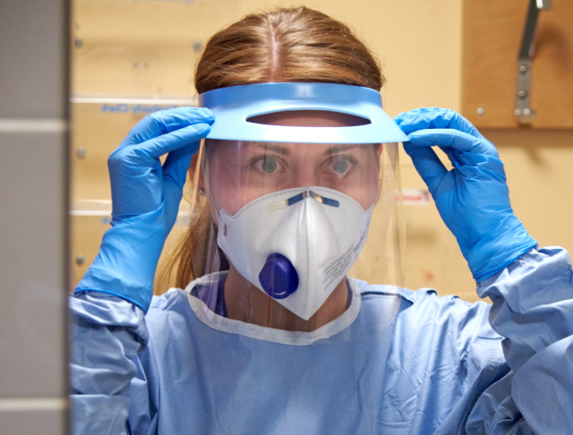 Kvinna med skyddsvisir och skyddskläder