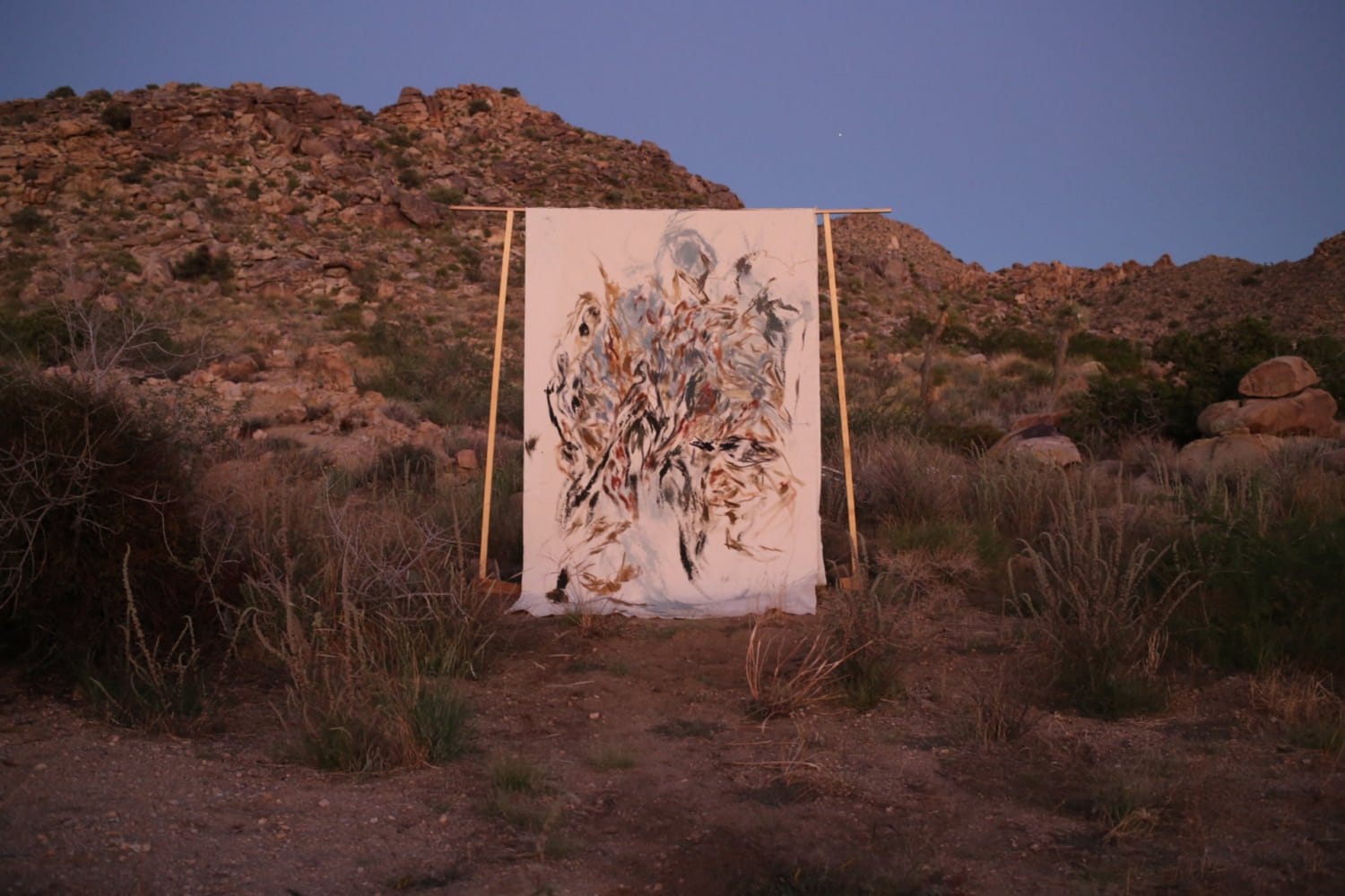 canvas painting hung on standing A-frame in the Mojave Desert