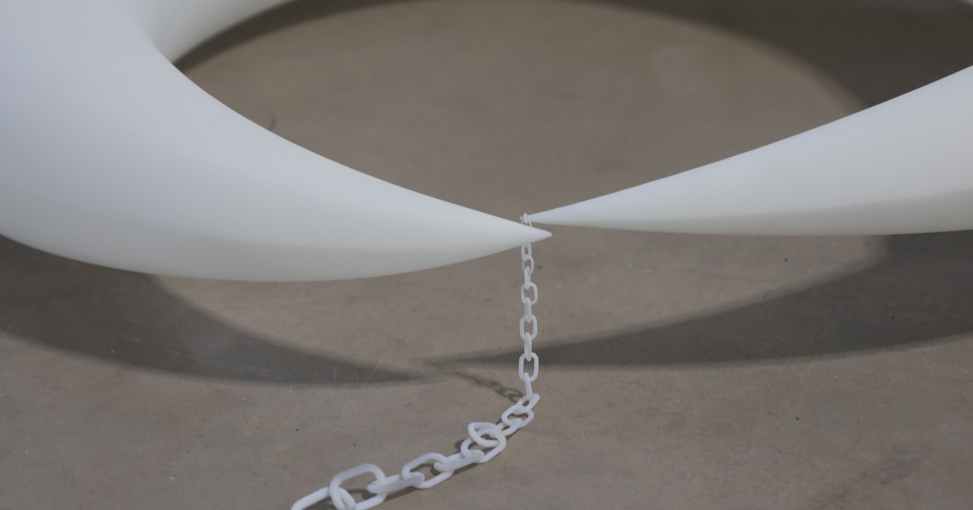 Close-up photograph of an enormous claw connecting to a tiny chain.