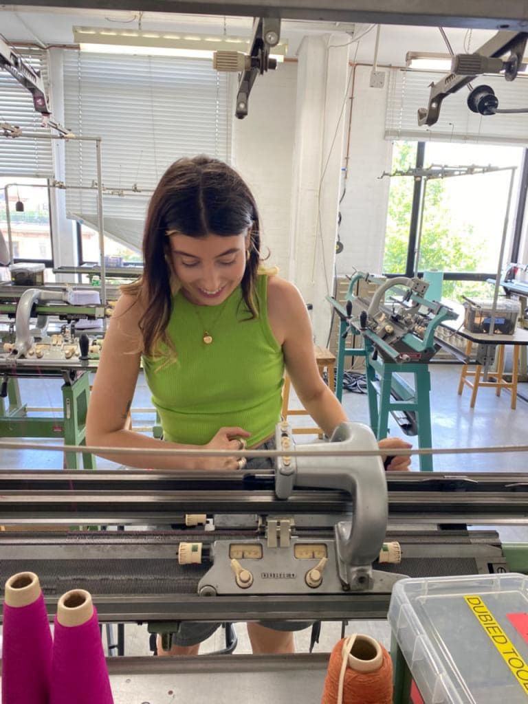 Image of Adélie standing at a Dubied knitting machine in the knit room at the RCA.