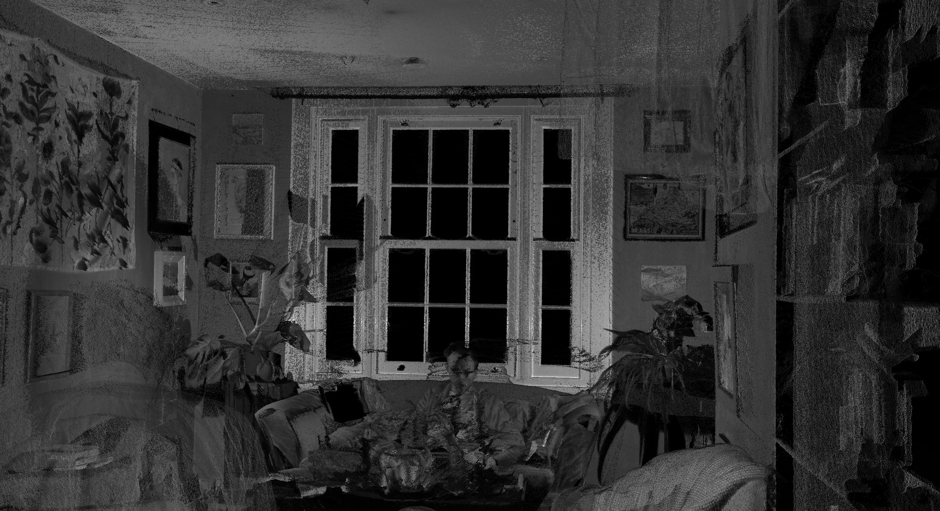 Black and white 3D scan image of a living room with plants inside and someone sitting on a sofa