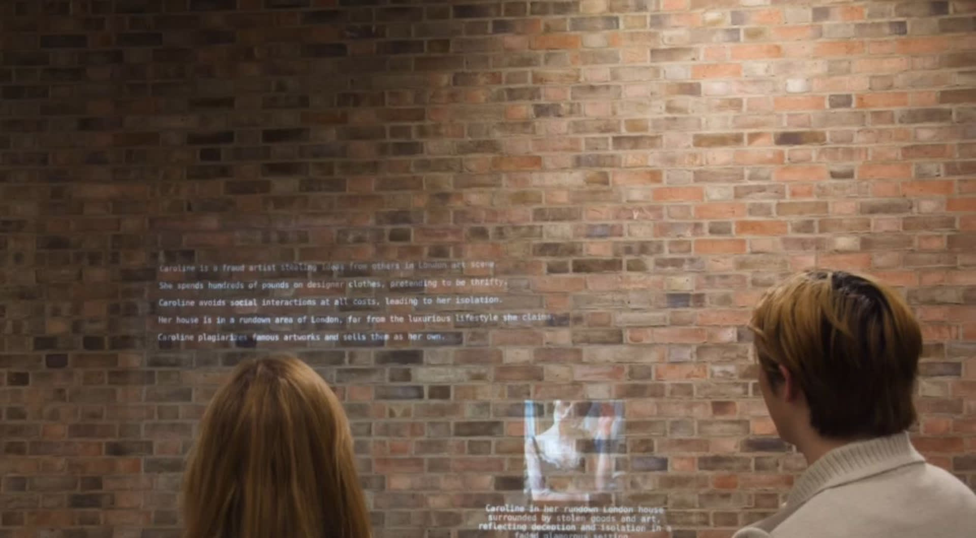 two individuals looking at projection of looooop exhibition 