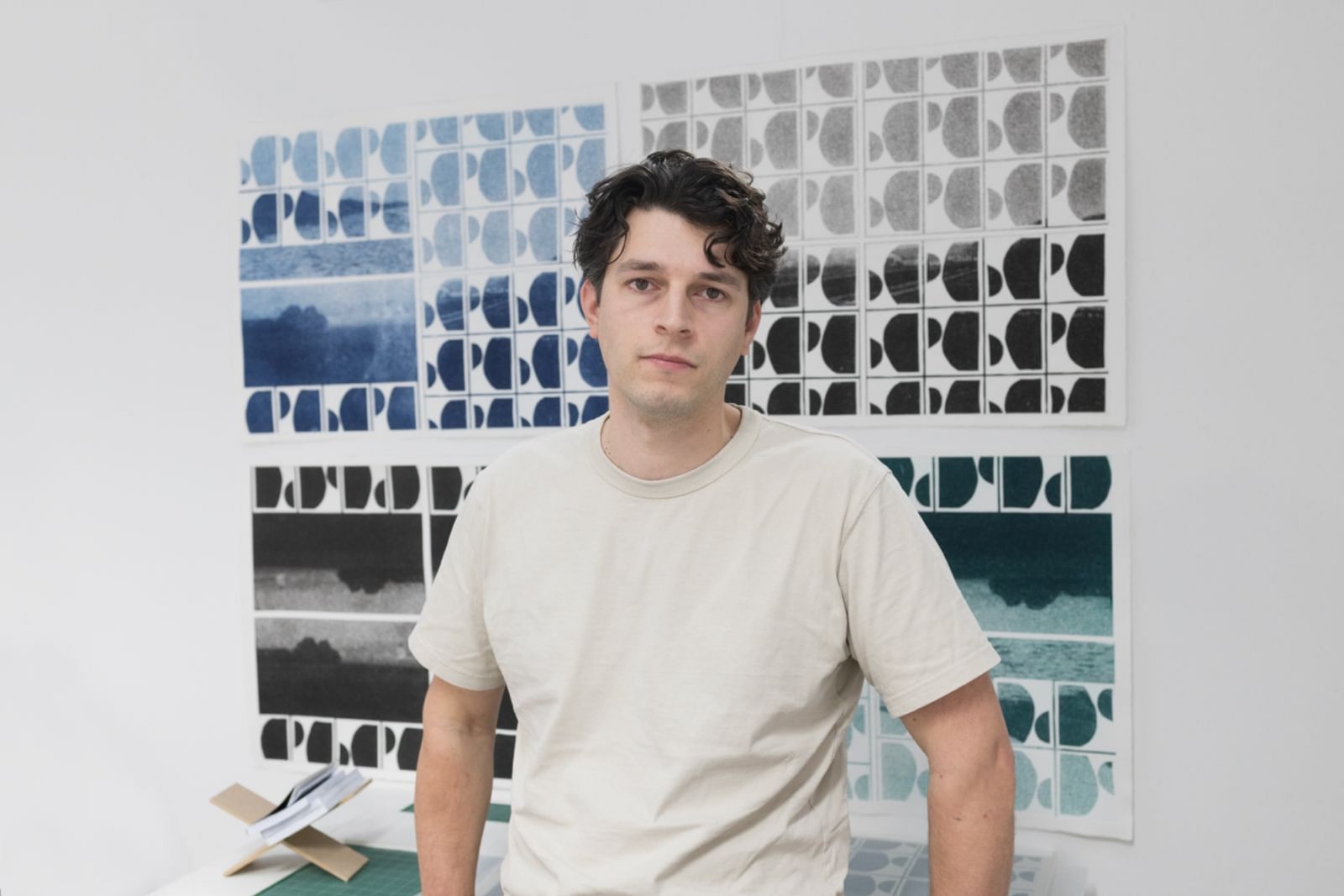 photo of man looking miserable in front of some artwork falling off the wall