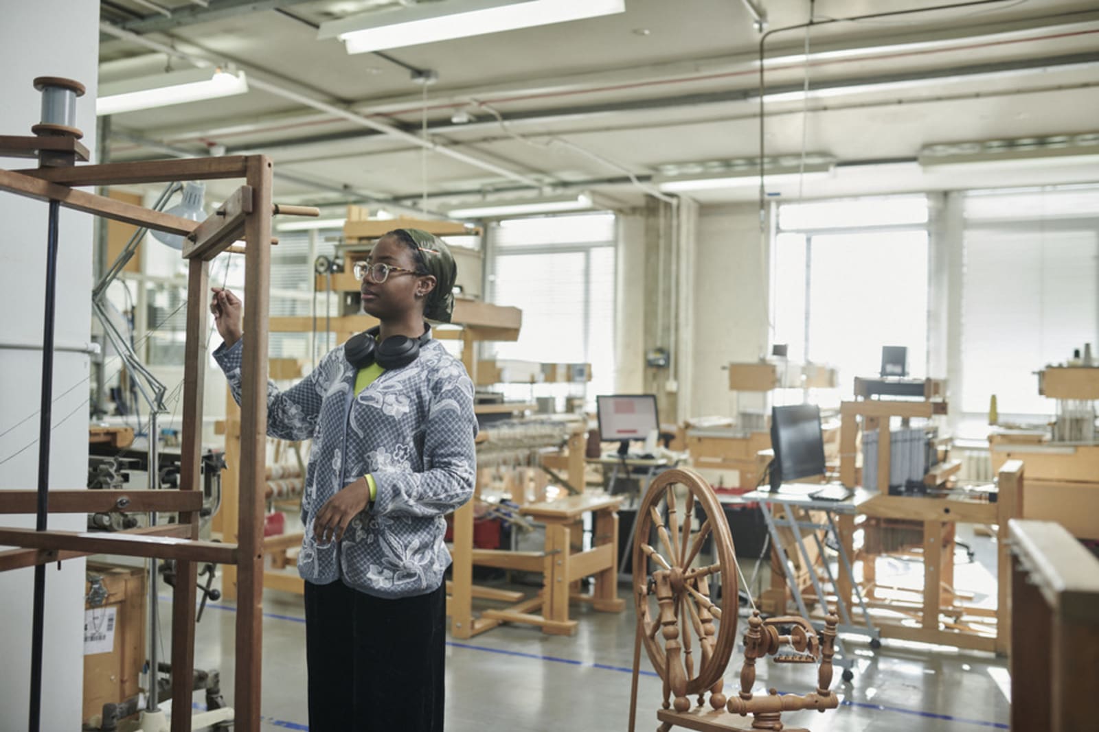 Khadija Standing next to a warping mill in the RCA textiles workshop area, specifically where the looms are. Facing sideways.