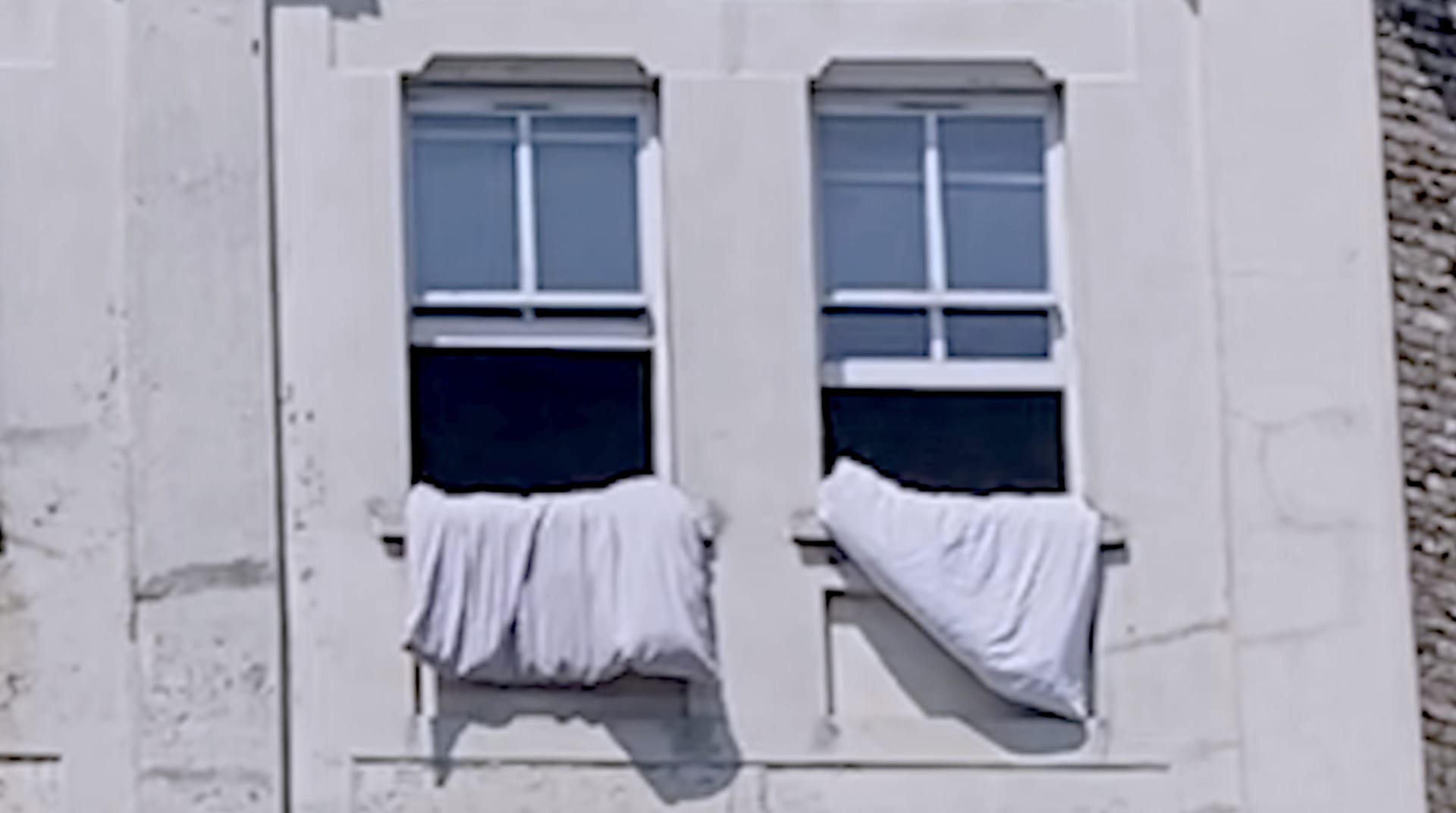 a photo of two open windows with duvets hanging out 