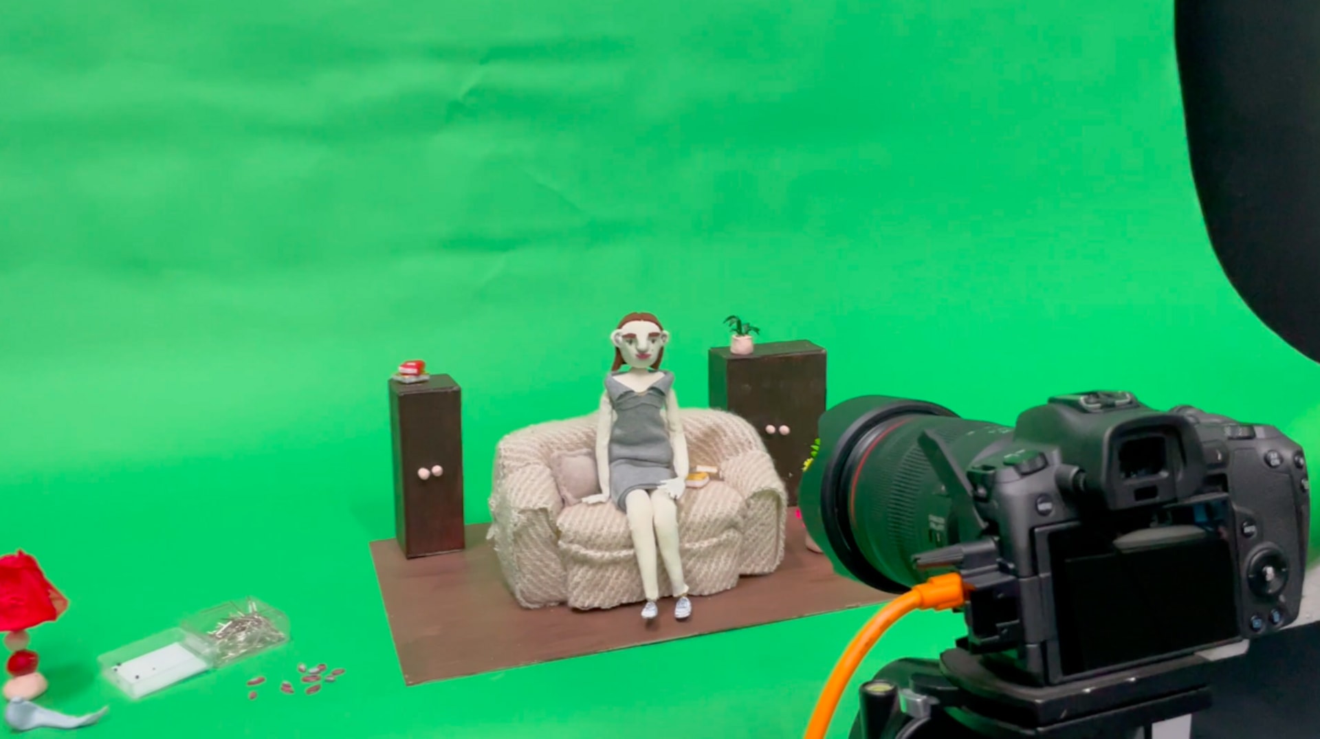 Puppet sitting on a sofa in front of a green screen, in a capture studio.