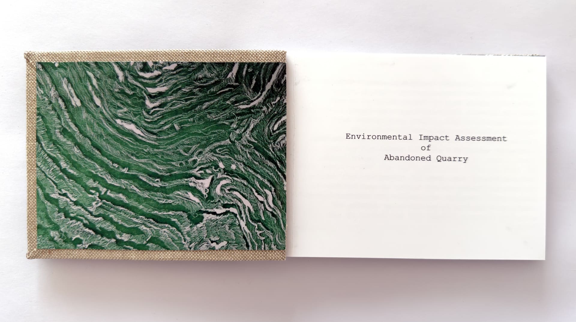 Front cover of artist book with drawing of an open pit mine and title page.