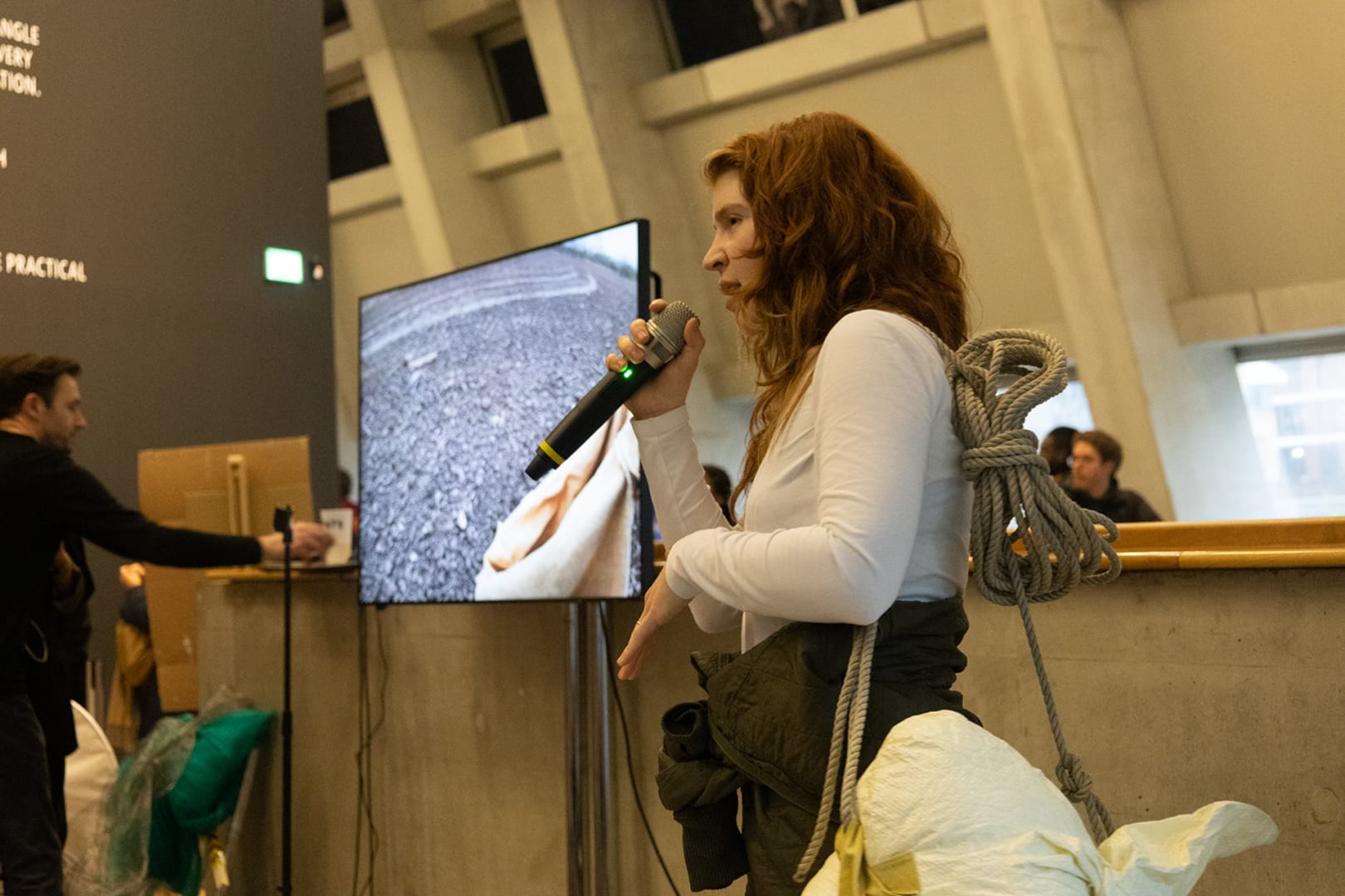 The artist performs to an audience at the Tate Modern, with a film playing on a screen in 