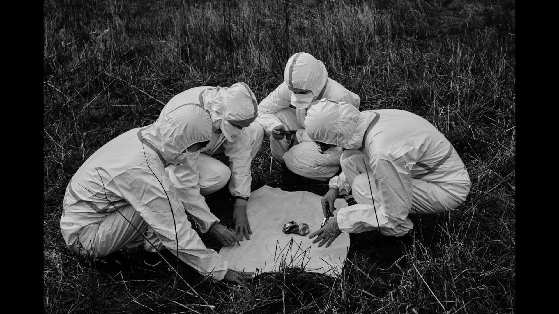 A still from the final film in black and white with all artists present and observing one of the 'artefacts' discovered.