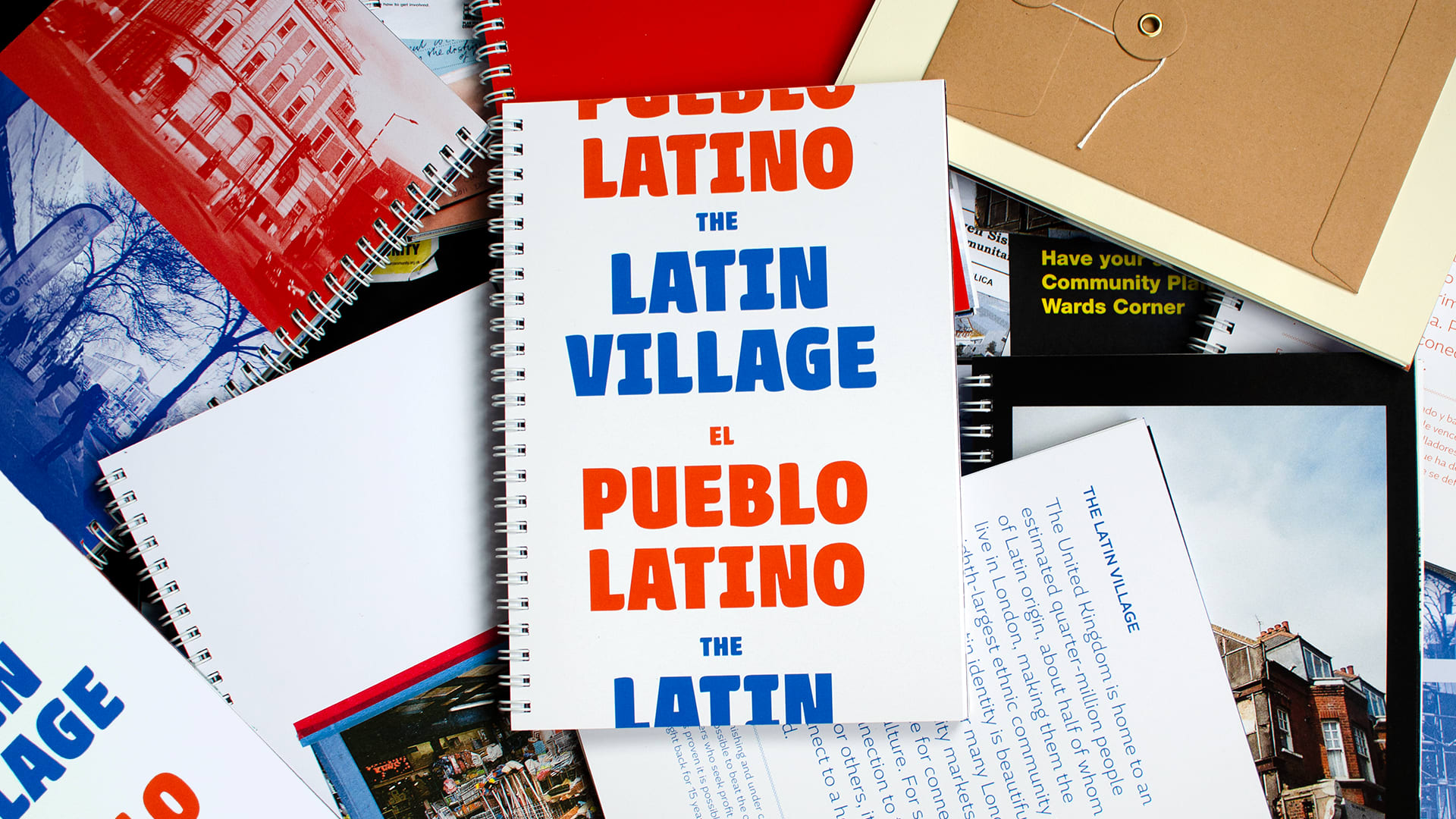 A spiral bound publication with the title "The Latin Village" and "El Pueblo Latino" laying on several other open publications 