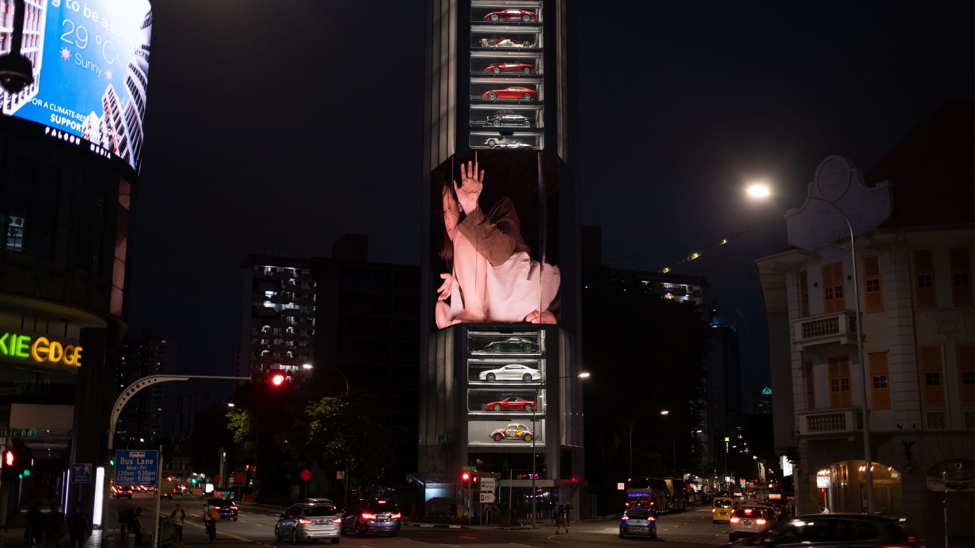 A giant human inside a box on a large LED screen on a tall building in Singapore.