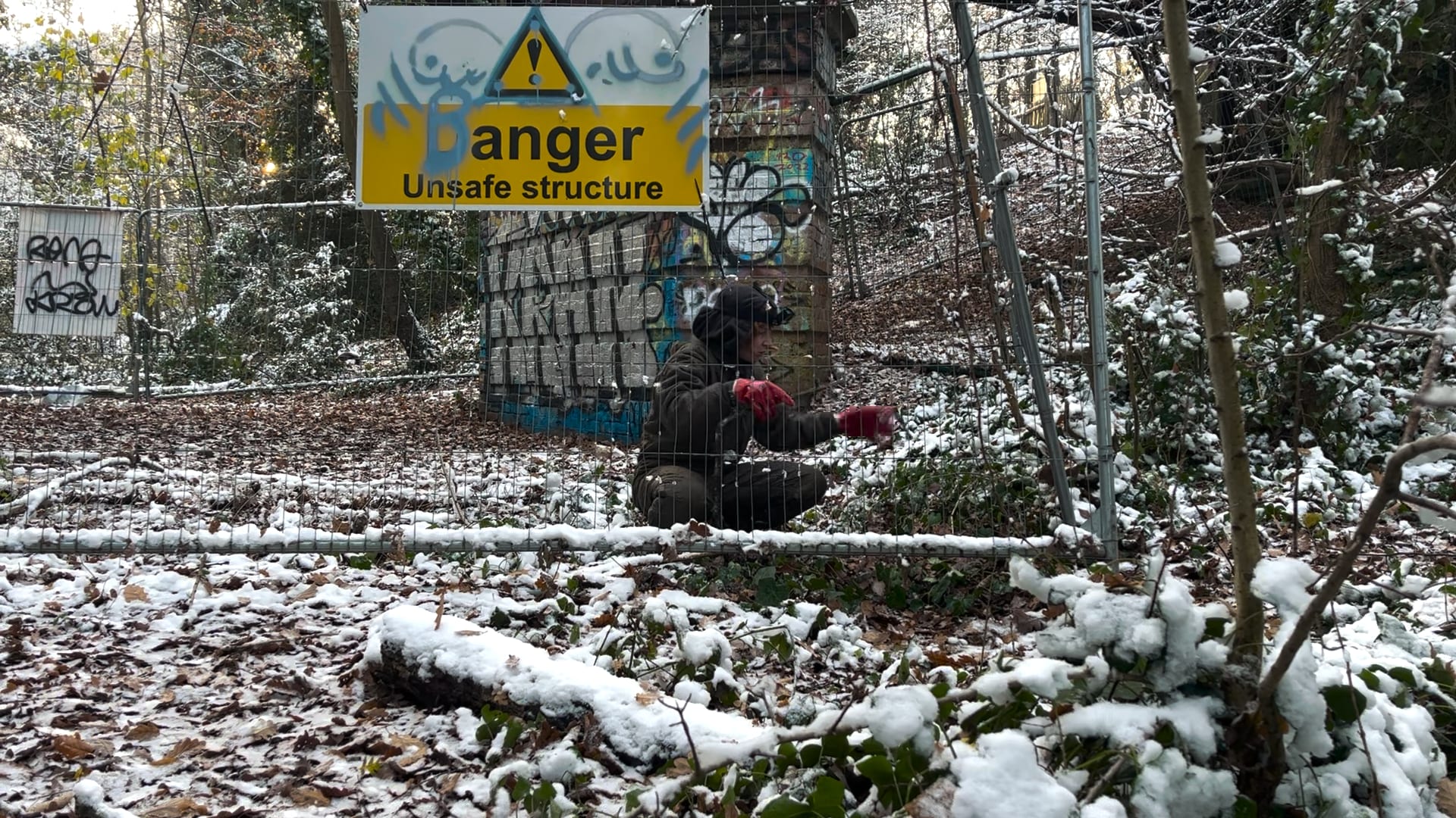 Film still from The Raging Hosts, performer inspects metal object in the woods.